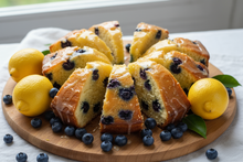 Load image into Gallery viewer, Lemon Blueberry Cake slices with lemons and blueberries around it
